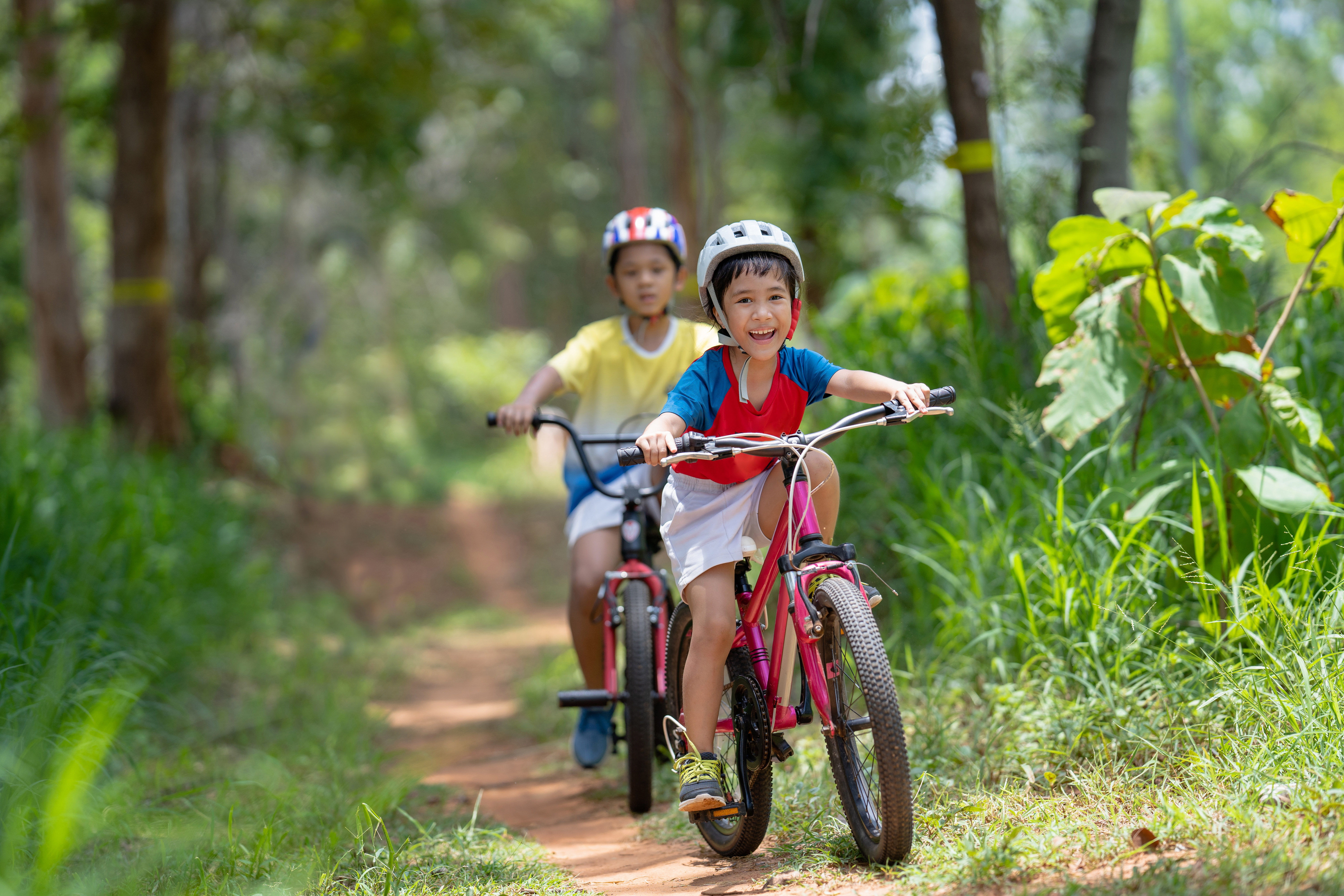 Two children cycling in the woods, smiling